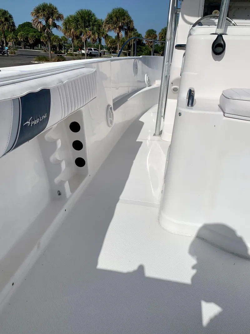 Slide: The Image of 2004 Pro-Line 25 Sport boat interior with white seating and rod holders. - 13
