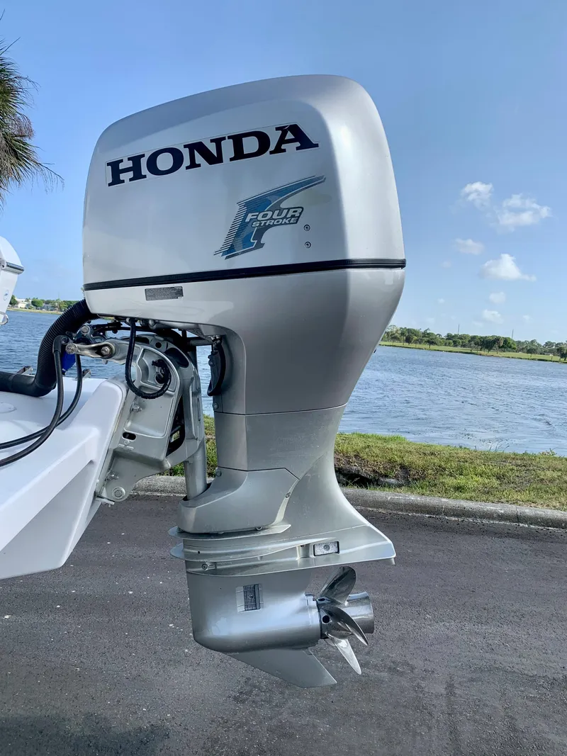 Slide: The Image of Honda outboard motor on a 2004 Pro-Line 25 Sport boat by the water. - 15