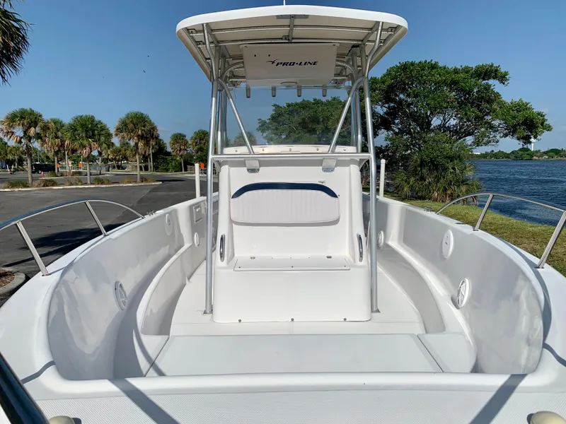 Slide: The Image of 2004 Pro-Line 25 Sport boat with T-top, docked near a scenic waterfront. - 23