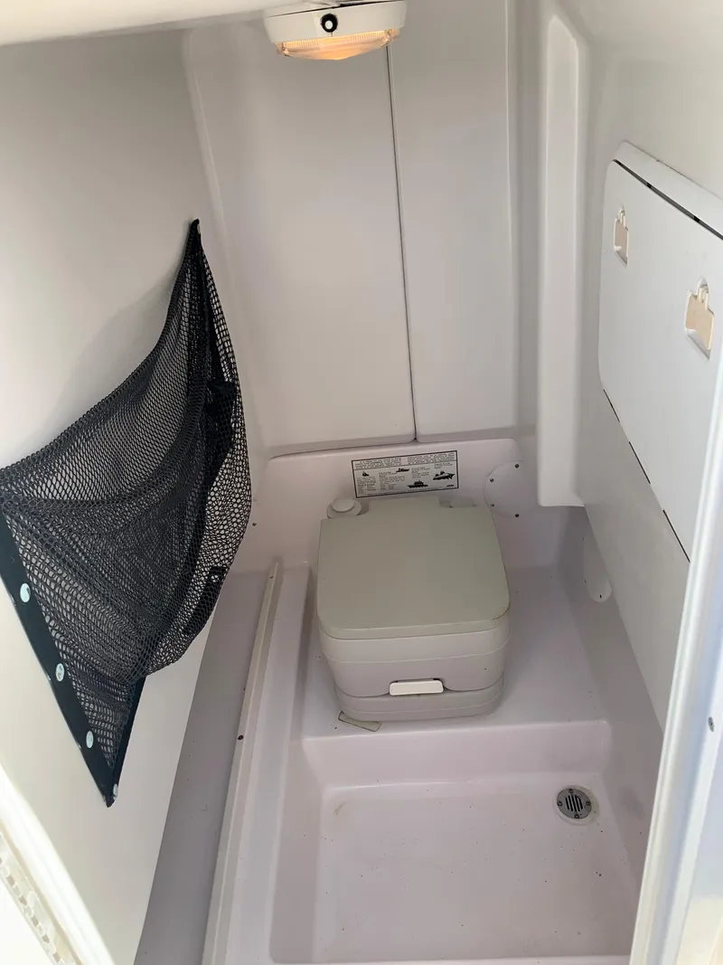 Slide: The Image of 2004 Pro-Line 25 Sport boat interior with portable toilet and storage. - 8