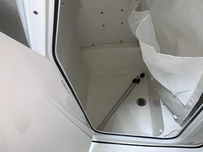 Slide: The Image of 2024 Key West 210 Bay Reef storage compartment with white interior and drainage system. - 7