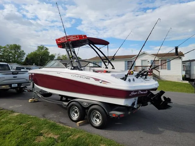 Slide: The Image of 2020 Tahoe 700 boat on trailer with fishing rods, parked in residential area. - 7