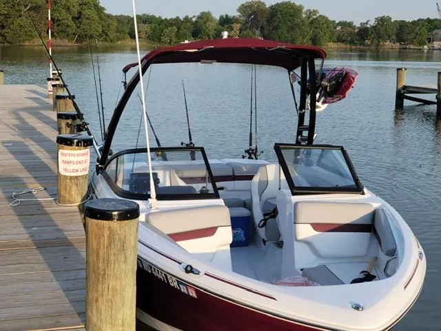 Slide: The Image of 2020 Tahoe 700 boat docked at a serene lake with fishing rods. - 8