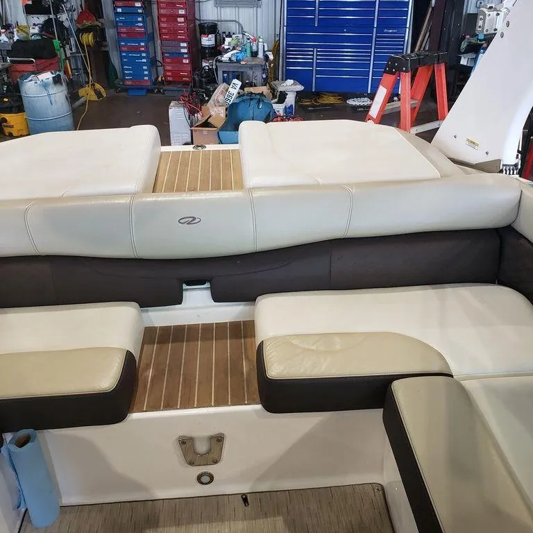 Slide: The Image of 2014 Regal 2100 boat interior with beige and brown seating in a workshop. - 3