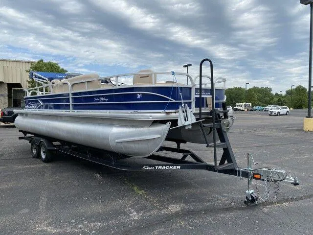 Slide: The Image of 2017 Sun Tracker Fishin' Barge 24 DLX pontoon boat on a trailer in a parking lot. - 3