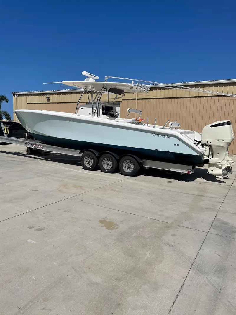 Slide: The Image of 2004 Venture 34 Open boat on trailer, parked outdoors under clear blue sky. - 3