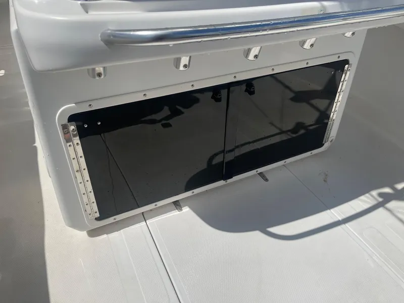 Slide: The Image of 2004 Venture 34 Open boat storage compartment with black panel and rod holders. - 8
