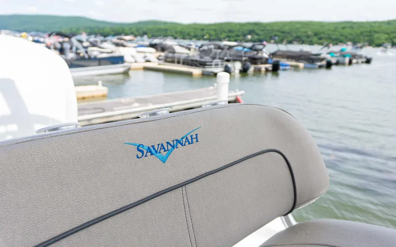 Slide: The Image of 2023 Savannah 190 IS boat seat at marina with docked boats in background. - 17
