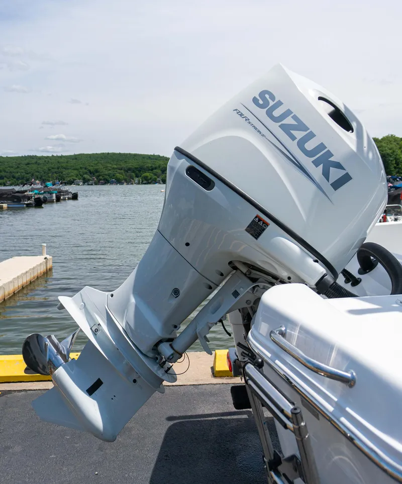 Slide: The Image of Suzuki outboard motor on a 2023 Savannah 190 IS boat docked by a lake. - 20