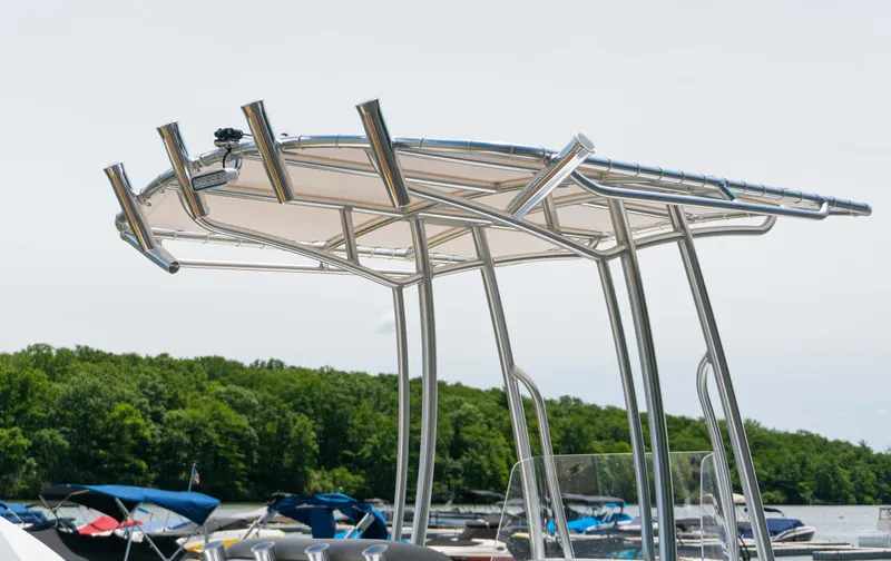 Slide: The Image of 2023 Savannah 190 IS boat with a sleek metal canopy, docked near a forested shoreline. - 4