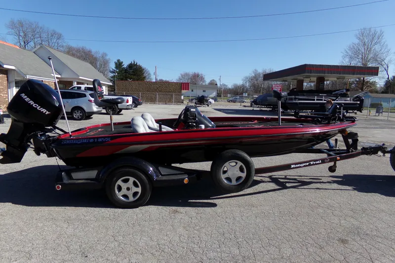 The Image of 2000 Ranger 518SVX Comanche boat on trailer, parked outdoors, featuring a Mercury outboard motor. - 0