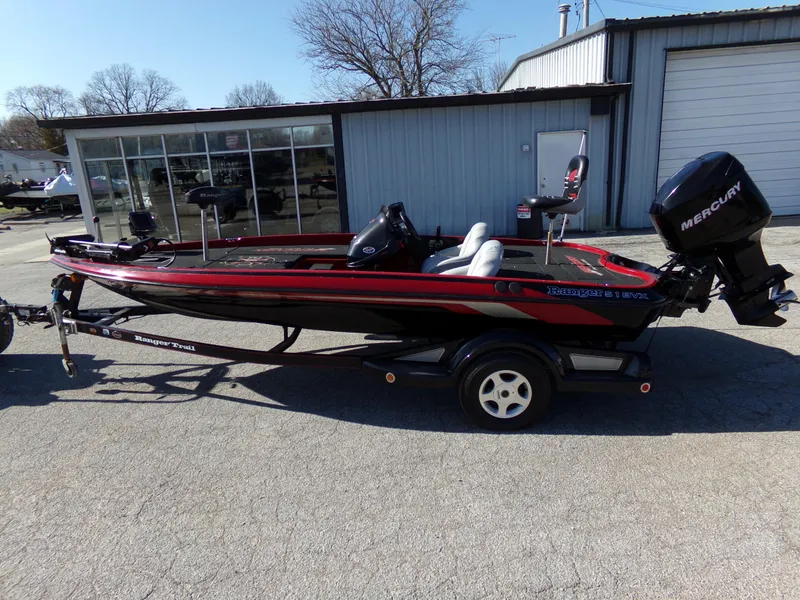 Slide: The Image of 2000 Ranger 518SVX Comanche boat with Mercury engine, parked outside a garage. - 11