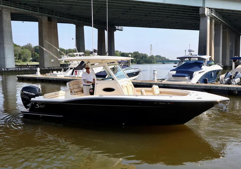 Slide: The Image of 2016 Scout 255 LXF boat docked under a bridge, with a person onboard. - 34