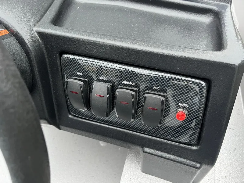 Slide: The Image of 2024 Lowe Legacy boat dashboard with control switches and horn button. - 10