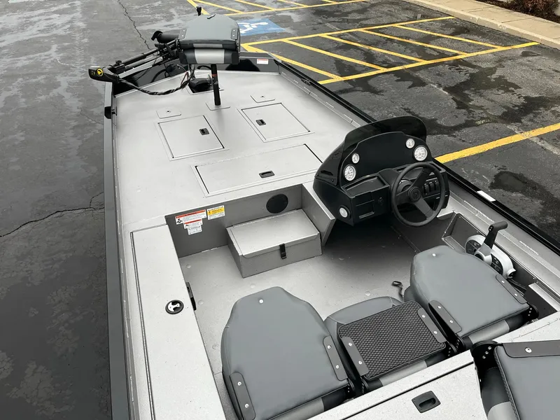 Slide: The Image of 2024 Lowe Legacy boat interior with steering console and seating in a parking lot. - 7