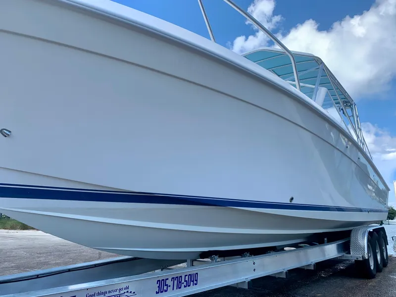 Slide: The Image of 2003 Contender 35 Express Side Console boat on a trailer under a blue sky. - 10