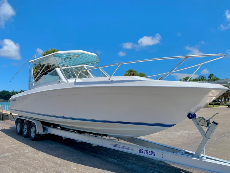 Slide: The Image of 2003 Contender 35 Express Side Console boat on a trailer under a clear blue sky. - 2
