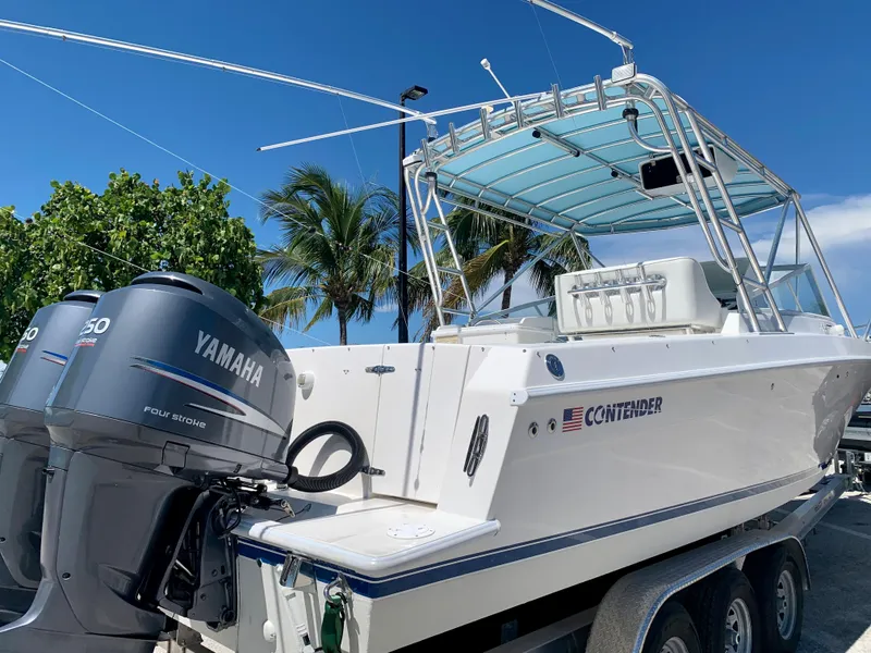 Slide: The Image of 2003 Contender 35 Express Side Console boat with Yamaha engines, docked under a clear blue sky. - 28