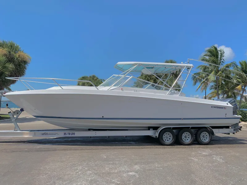 Slide: The Image of 2003 Contender 35 Express Side Console boat on a trailer, palm trees in the background. - 3