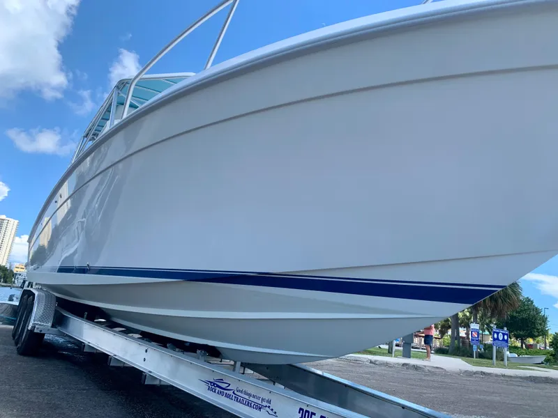 Slide: The Image of 2003 Contender 35 Express Side Console boat on a trailer, clear sky background. - 9