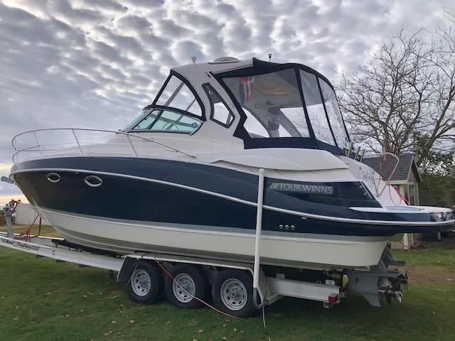 Slide: The Image of 2014 Four Winns 355V boat on a trailer, parked on grass under a cloudy sky. - 4