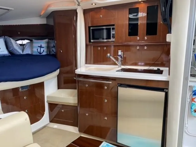 Slide: The Image of 2014 Four Winns 355V boat interior with kitchenette, bed, and seating area. - 47