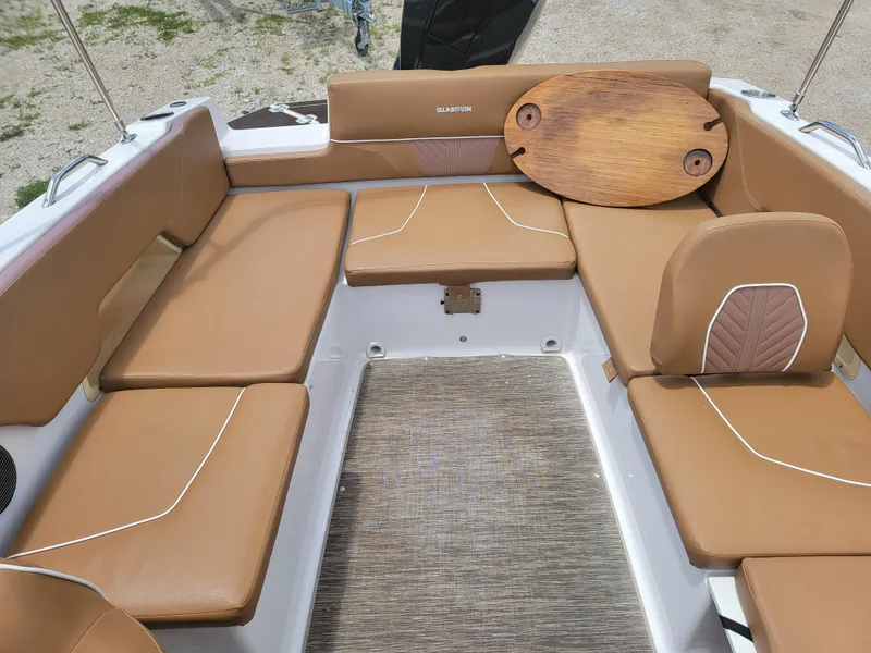 Slide: The Image of 2019 Glastron GTD 220 boat interior with tan leather seating and a wooden table. - 13