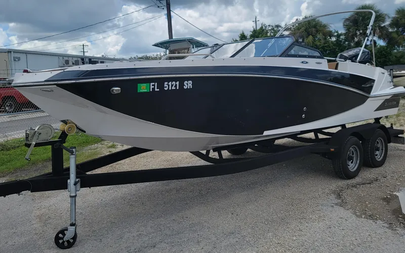 Slide: The Image of 2019 Glastron GTD 220 boat on a trailer, black and white exterior, parked outdoors. - 14
