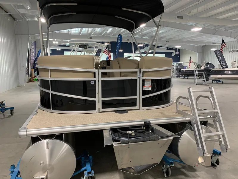 Slide: The Image of 2024 Starcraft LX22 R pontoon boat in showroom, front view with ladder. - 2