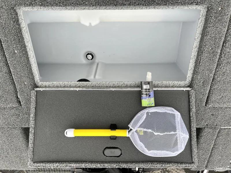 Slide: The Image of 2022 Lund 1875 Impact XS boat storage compartment with fishing net and spray bottle. - 7