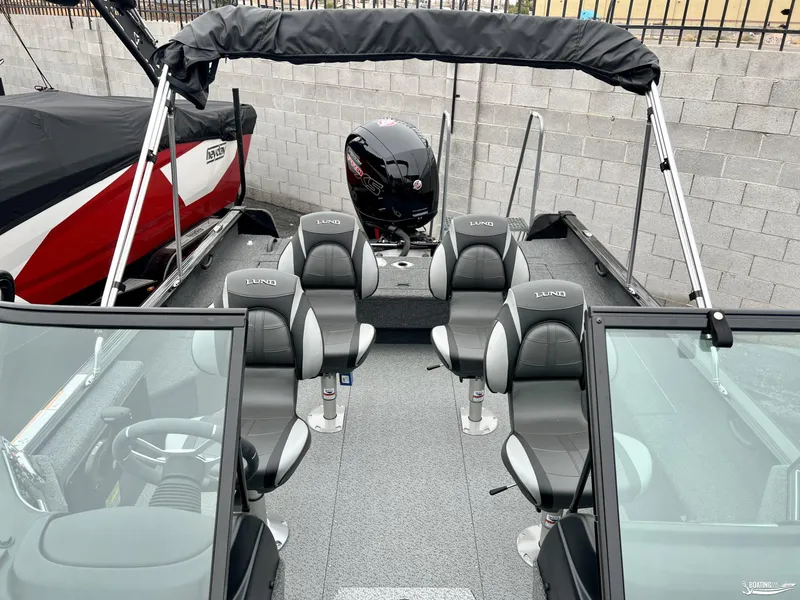 Slide: The Image of 2022 Lund 1875 Impact XS boat interior with seating and motor, parked near a wall. - 8