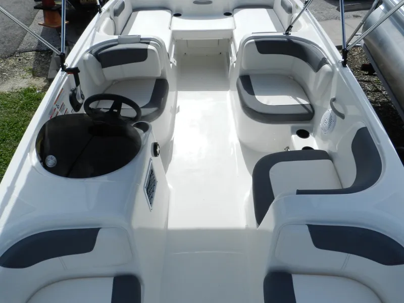 Slide: The Image of 2025 Bayliner E18 boat interior with gray and white seating, steering wheel, and open deck layout. - 12