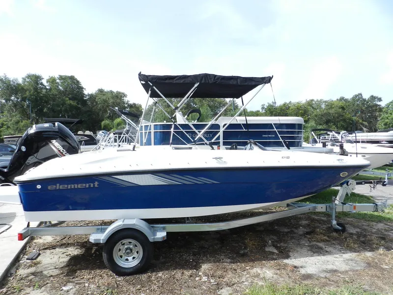 Slide: The Image of 2025 Bayliner E18 boat with blue hull on trailer, parked outdoors. - 2
