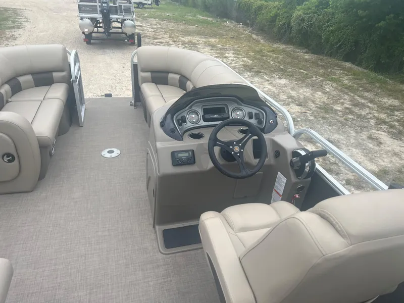 Slide: The Image of 2023 Sun Tracker Party Barge 22 RF DLX interior with beige seating and steering console. - 2