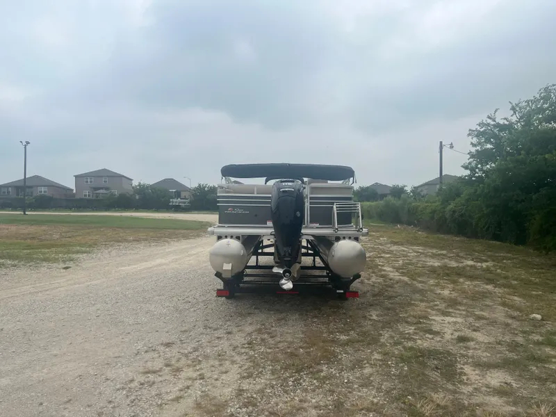 Slide: The Image of 2023 Sun Tracker Party Barge 22 RF DLX pontoon boat on a trailer in a grassy area. - 3