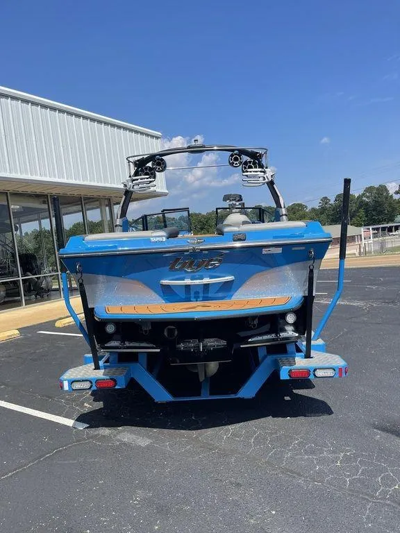 Slide: The Image of 2017 Tigé RZX2 blue wakeboard boat parked outside a building. - 2