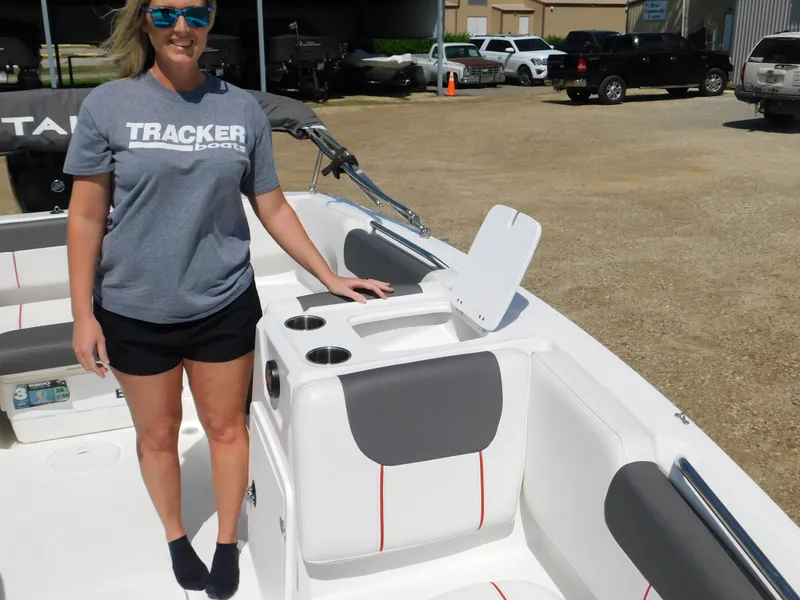 Slide: The Image of Woman standing on a 2023 Tahoe 1950 boat, showcasing seating and storage. - 16