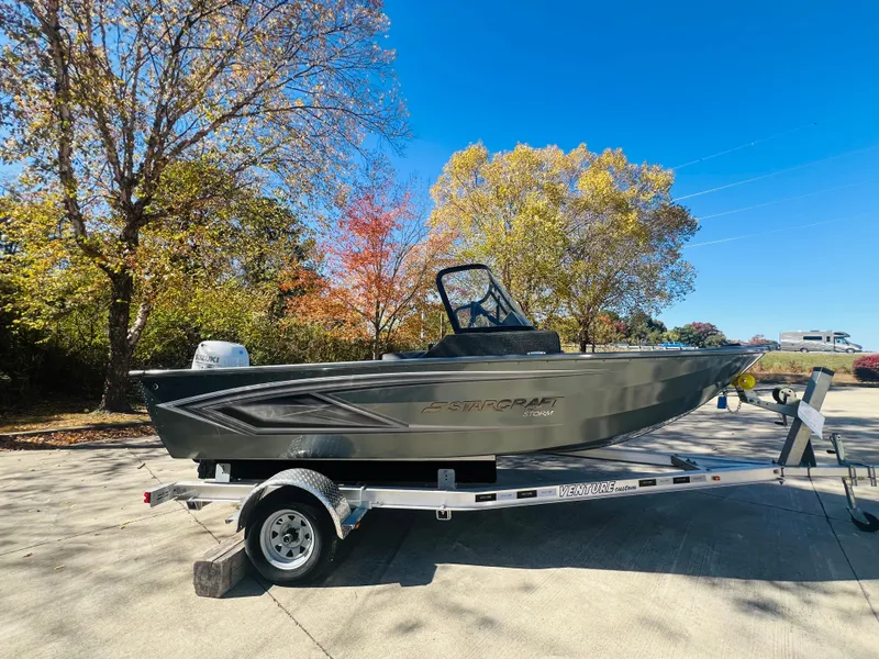 The Image of 2023 Starcraft Storm 166 DC boat on trailer, surrounded by autumn trees. - 0