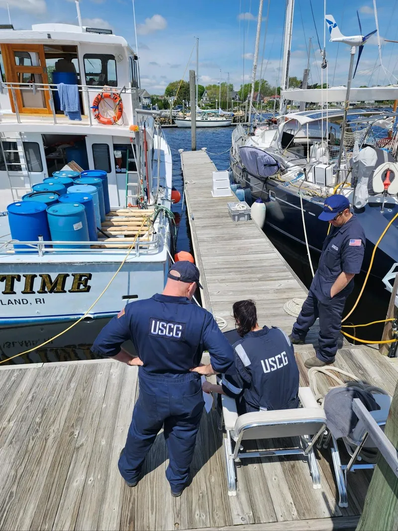 Slide: The Image of USCG officers inspecting docked boats, including a 1980 Tuna Rose Brothers model, on a sunny day. - 43