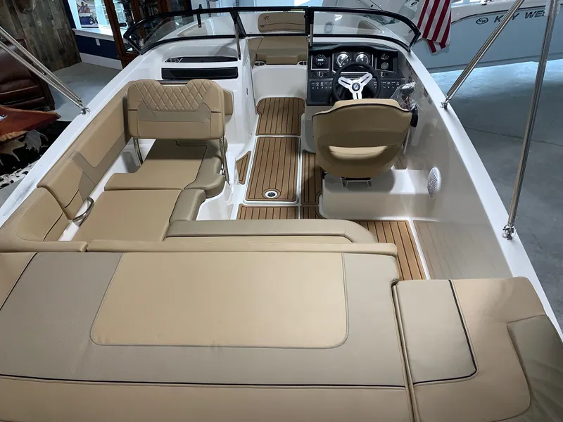 Slide: The Image of 2024 Bayliner VR5 boat interior with beige seating and wood accents. - 13