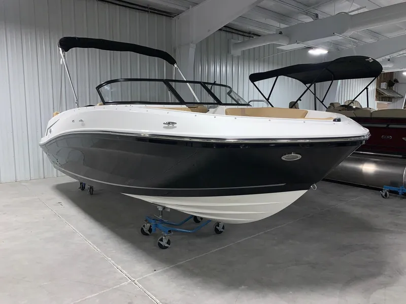 Slide: The Image of 2024 Bayliner VR5 boat in showroom, black and white exterior, with canopy. - 2