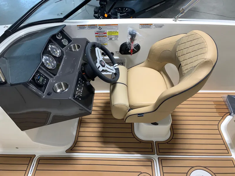 Slide: The Image of 2024 Bayliner VR5 boat cockpit with beige captain's chair and wooden flooring. - 8