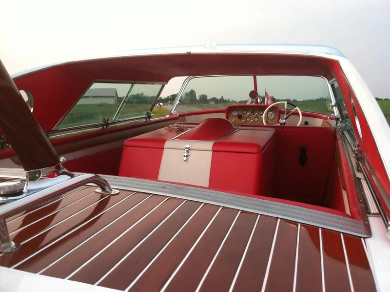 Slide: The Image of 1959 Century Coronado boat interior with red and white upholstery, wooden deck, and classic dashboard. - 13
