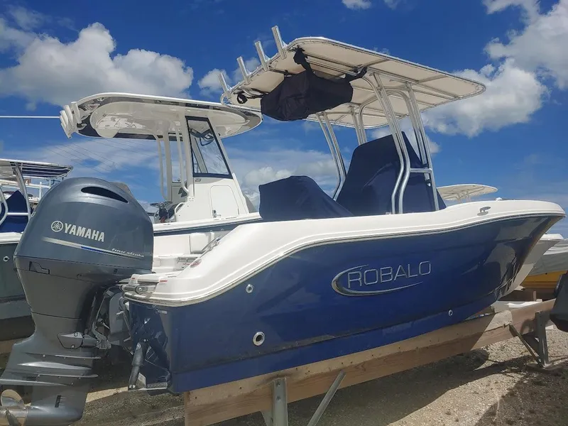 Slide: The Image of 2022 Robalo R180 Center Console boat with Yamaha engine, parked under a blue sky. - 1