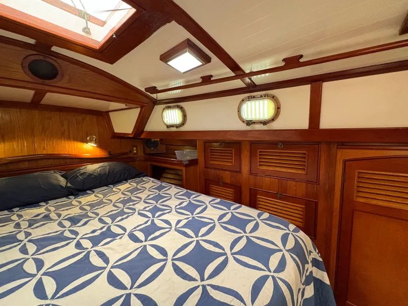 Slide: The Image of Cozy cabin interior of 1984 Shannon Aegean 51 sailboat with wood paneling and patterned bedding. - 26