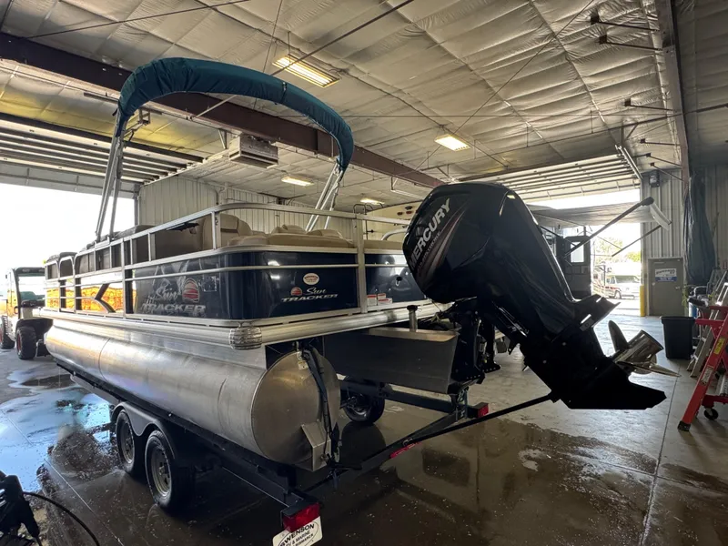 Slide: The Image of 2019 Sun Tracker SportFish 22 DLX pontoon boat in a garage with Mercury outboard motor. - 4