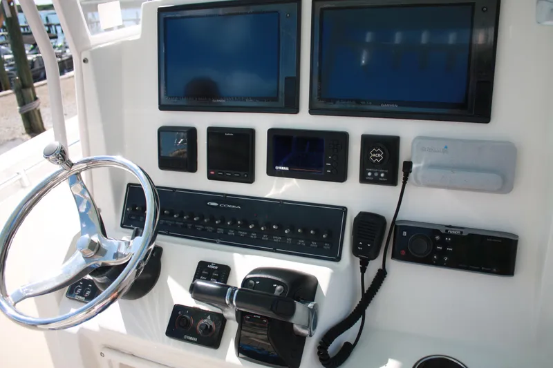 Slide: The Image of Das Bild zeigt das Steuerpult eines Cobia 301 Center Console Bootes von 2018 mit mehreren Bildschirmen und Bedienelementen. - 10
