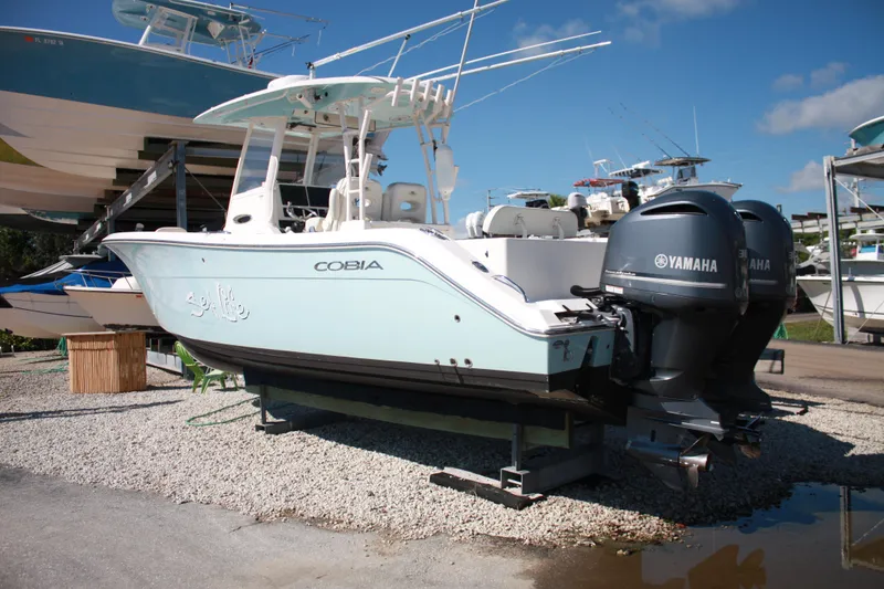 Slide: The Image of Ein Cobia 301 Center Console Boot von 2018 mit zwei Yamaha Außenbordmotoren, auf einem Kiesplatz geparkt. - 8