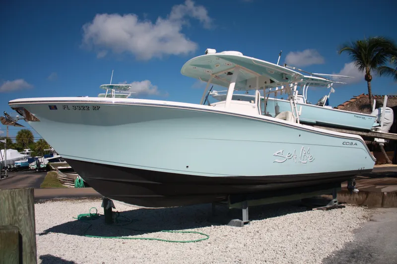 Slide: The Image of Ein 2018er Cobia 301 Center Console Boot steht auf einem Kiesbett unter einem klaren blauen Himmel. - 2