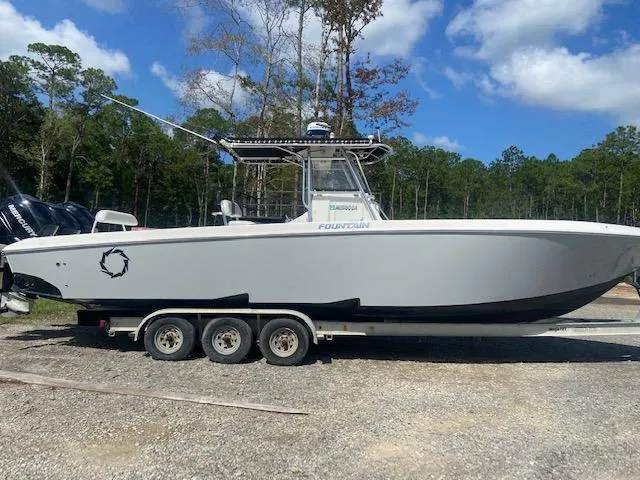 Slide: The Image of 2004 Fountain 34 CC boat on a trailer, parked outdoors with trees in the background. - 3